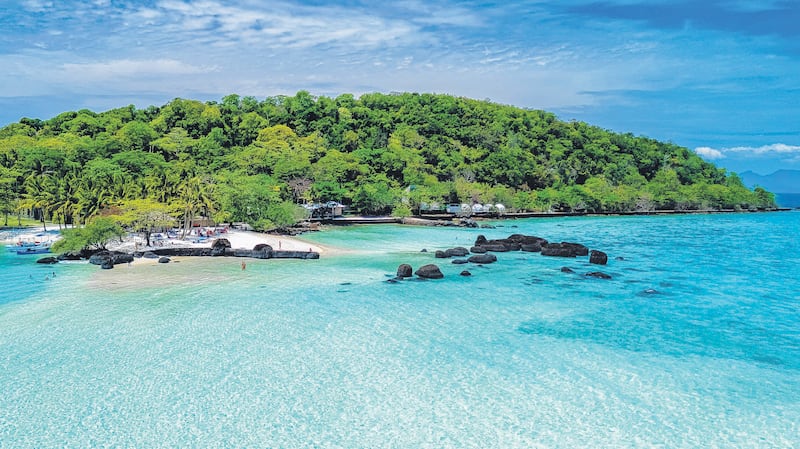 Breathtaking coastal vista showcasing a lush island with vibrant green trees and soft sandy beaches. Vibrant turquoise waters create an idyllic tropical atmosphere,Koh Kham Thailand