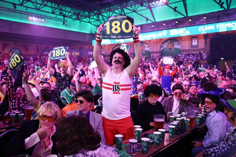 A fan wearing a 118 costume holds up a 180 sign ahead of the second round match between Stephen Bunting and Nitin Kumar. Photograph: James Fearn/Getty Images