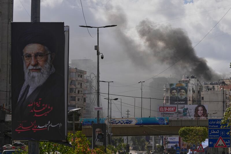 A portrait of Iran’s late supreme leader Ayatollah Ali Khamenei, left, is seen as smoke rises following an Israeli airstrike in Dahiyeh, Beirut’s southern suburbs, Lebanon. Photograph: Hassan Ammar/AP