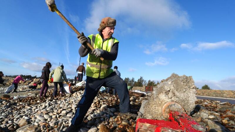 A volunteer clears destroyed seating during the clean-up of the promenade and beach at Spiddal on Saturday, which was severely damaged by the storms and high tides at Spiddal the previous week. Photograph: Joe O’Shaughnessy