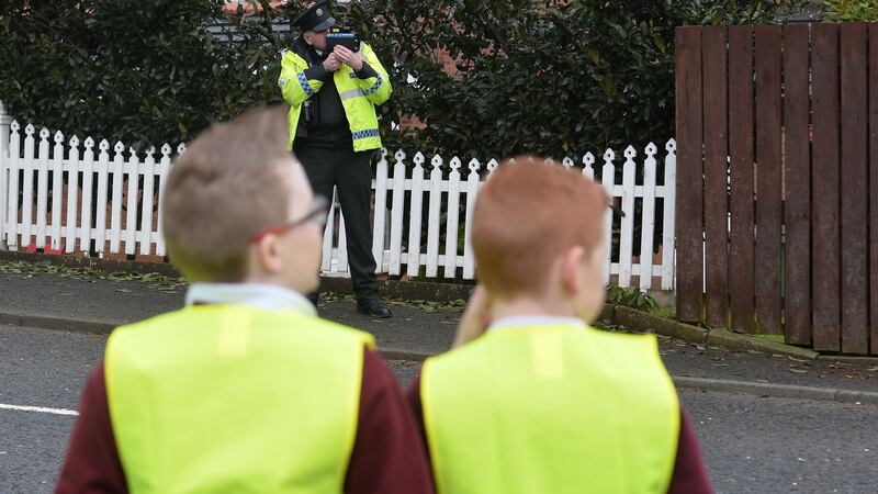 Pupils from Annahilt Primary School in Co Down watch as a police officer keeps an eye out for speeding drivers outside the school. Photograph:  Colm Lenaghan/Pacemaker Press