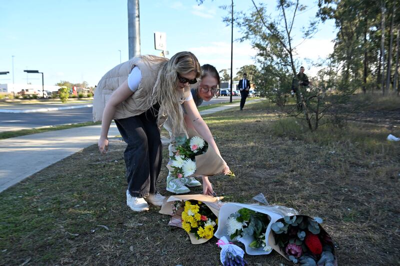 Two women lay flowers on the side the road some 500m from the site of a bus crash in Australia's Hunter wine region north of Sydney. Photograph: Saeed Khan/AFP/Getty