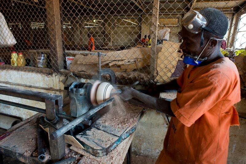 A prisoner in Luzira maximum security prison using a lathe to craft a wooden ornament.  Photograph: Lar Boland