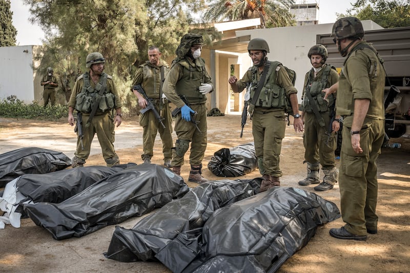 Israeli soldiers collecting the bodies of Israelis killed in the village of Kfar Azza, near the fenced border with Gaza. Photograph: Sergey Ponomarev/New York Times
                      