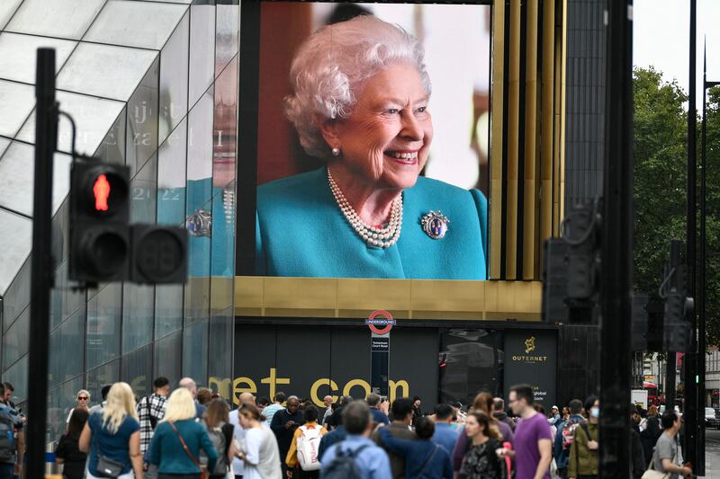 Pedestrians walks past a portrait of Queen Elizabeth II on a street in London. Photograph: Stefanie De Sakutin/AFP via Getty Images