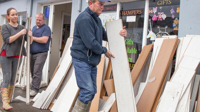 Shop owner April Soames gets some help from Dominic McCahill and local councillor Noel Jordan as she removes the destroyed flooring from her shop in Donegal town. Photograph: North West Newspix