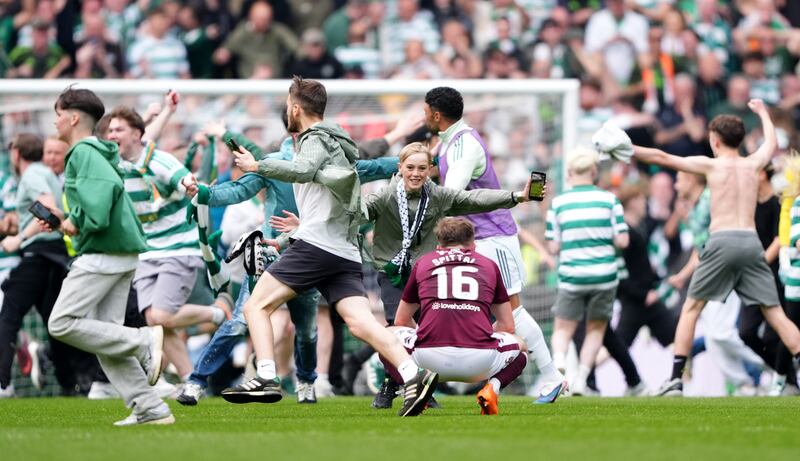 Celtic fans celebrate on the pitch after the third goal was scored. Photograph: Andrew Milligan/PA Wire