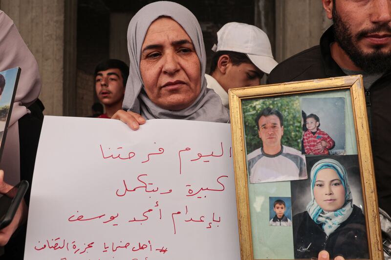 A woman holds photos of her relatives who were killed in the Tadhamon massacre in Damascus on Friday. Photograph: Mohammed Alrifai/EPA