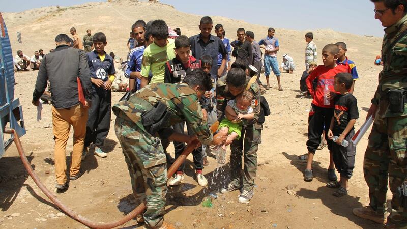 Peshmerga fighters wash the feet of a displaced Iraqi child from the northern Iraqi village of Hawija as families rest under the protection of Peshmerga forces some 50km northwest of Kirkuk after fleeing from Islamic State  jihadists on August 17th, 2016. Photograph: Marwan Ibrahim/AFP/Getty Images