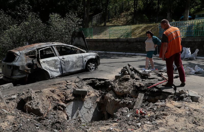 Two people look into a hole after debris fell outside an apartment building in a drone strike in Kyiv, Ukraine. Photograph: Sergey Dolzhenko/EPA