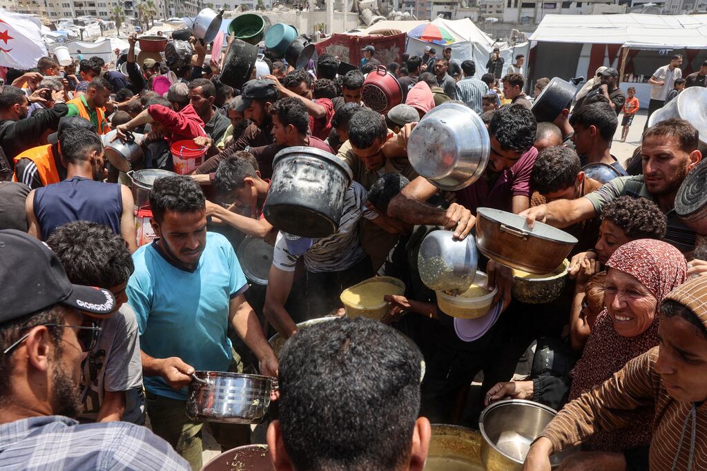 Palestinians at a hot meal distribution point at a displacement camp near Gaza City's port on Thursday. (Photo by Omar Al-Qattaa/ AFP)
