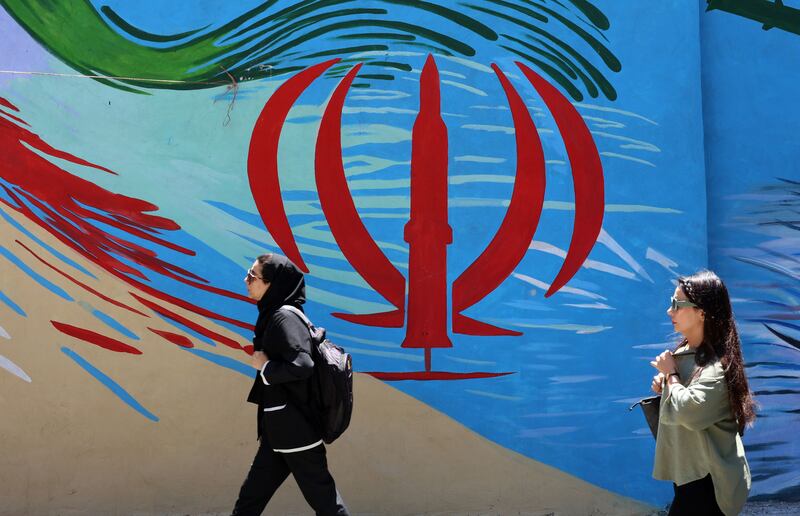 Iranians walk past a wall painting of Iran's national flag on a street in Tehran. Photograph: EPA
