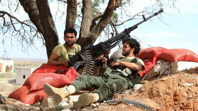 Rebel fighters rest with their weapons near sandbags in Al-Lataminah village, northern Hama countryside. Photograph: Ammar Abdullah/Reuters