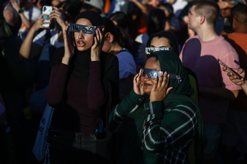 People use special protective glasses as they watch a near total solar eclipse from Primrose Hill in London. Photograph: Henry Nicholls/AFP via Getty Images