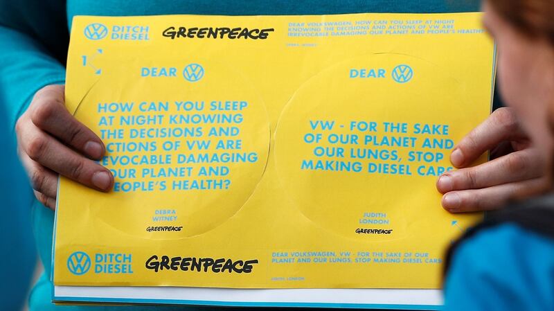 A Greenpeace volunteer holds stickers with messages after activists entered the vehicle park in a protest against Volkswagen diesel vehicles. Photograph:  Peter Nicholls/Retuers