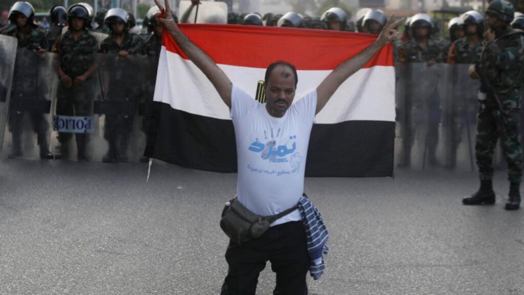 A member of the “Tamarod - Rebel!” petition drive against Mohamed Morsi gestures with an Egyptian flag in front of army soldiers standing guard in front of anti-Morsi protesters. Photograph: Reuters