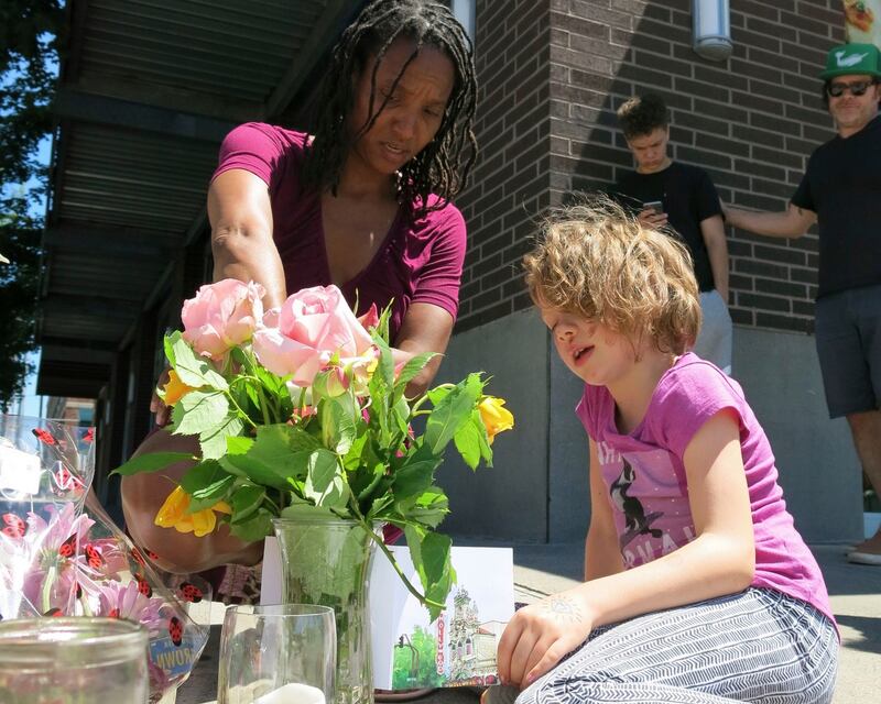 Angel Sauls, left, helps her stepdaughter, Coco Douglas arrange a sign and some painted rocks she made for a memorial in Portland, Oregon  for two bystanders who were stabbed to death while trying to stop a man who was yelling anti-Muslim slurs and acting aggressively toward two young women.  Photgraph: AP/Gillian Flaccus