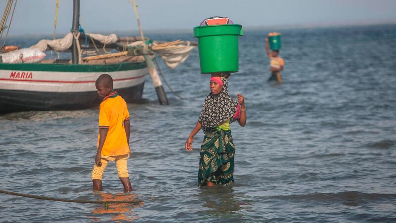 A woman balances a bucket on her head as she reaches the shore on December 11 at the beach in the community of Paquitequete, where thousands of displaced people have arrived in recent months. Photograph: Alfredo Zuniga/AFP via Getty
