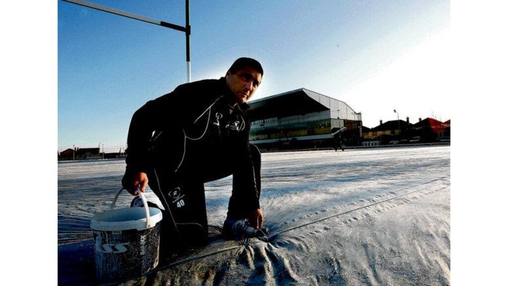 Connacht coach Michael Bradley helps cover the frozen over pitch at the Sportsground in Galway after the province's game with Leinster was called off. - (Photograph: James Crombie/Inpho)