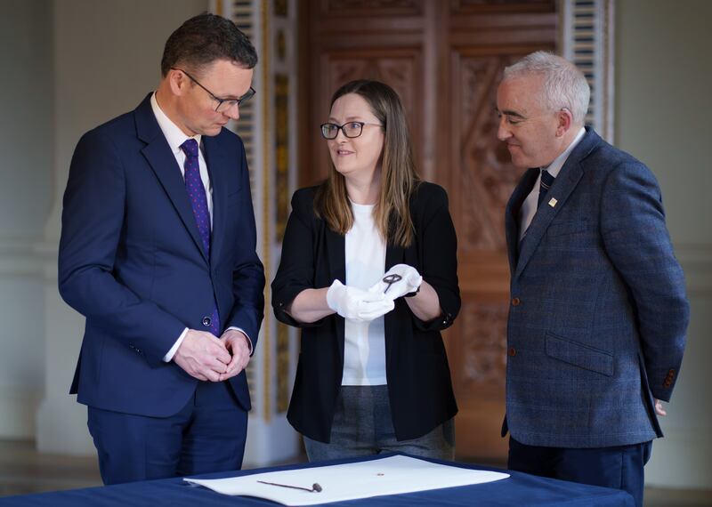 Minister Patrick O’Donovan and the National Museum's Joanne Gaffrey and Prof Cathal O’Donoghue inspect the early medieval brooch pin discovered by archaeologists at Ardshanbally as part of excavation works for the Adare bypass. Photograph: Fran Veale/Julien Behal Photography  
