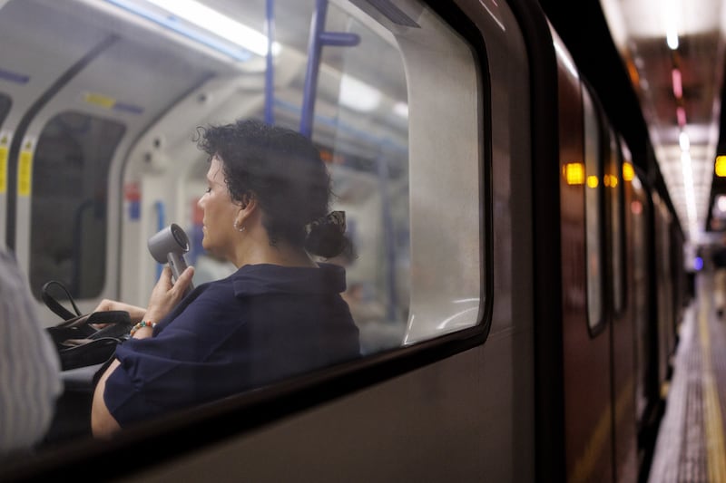 A person uses an electric fan to cool down as commuters travel on the London Underground as the UK is set to experience its hottest June day on record. Photograph: EPA