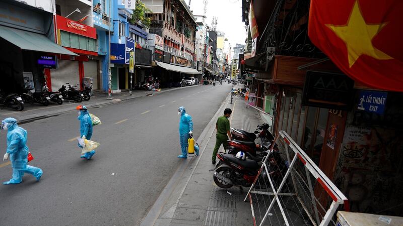 Medical workers collecting test samples from residents walk past in Ho Chi Minh City. Photograph:  Huu Khoa/AFP via Getty