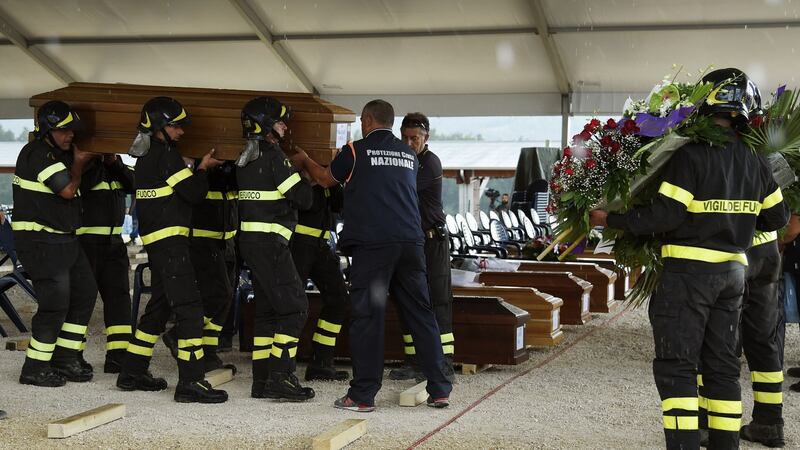 Firefighters carry a coffin in a tent complex in Amatrice, central Italy,  prior to a funeral ceremony for the victims of a recent earthquake, on August 30th, 2016.  Photograph: Andreas Solaro/AFP/Getty Images