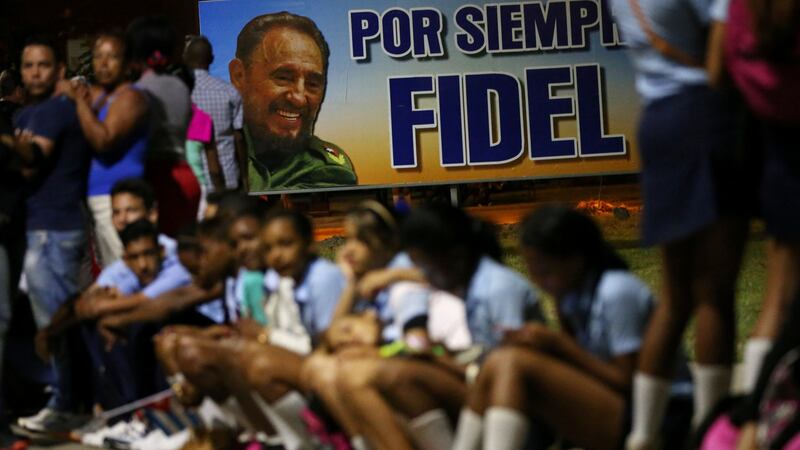 People rest on a sidewalk while waiting for the cortege carrying the ashes of Cuba’s former president Fidel Castro to drive toward Santa Ifigenia cemetery in Santiago de Cuba. Photograph: Carlos Garcia Rawlins/Reuters.