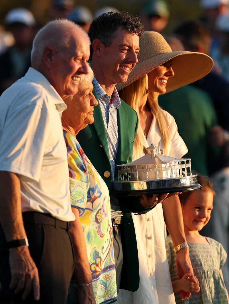 Rory McIlroy (C) of Northern Ireland poses with the Masters trophy during the Green Jacket Ceremony alongside father Gerry (L), mother Rosie (2nd L), wife Erica (2nd R) and daughter Poppy (R) after winning during the final round of the 2026 Masters Tournament at Augusta National Golf Club on April 12, 2026 in Augusta, Georgia. Photograph: Maddie Meyer/Getty Images
