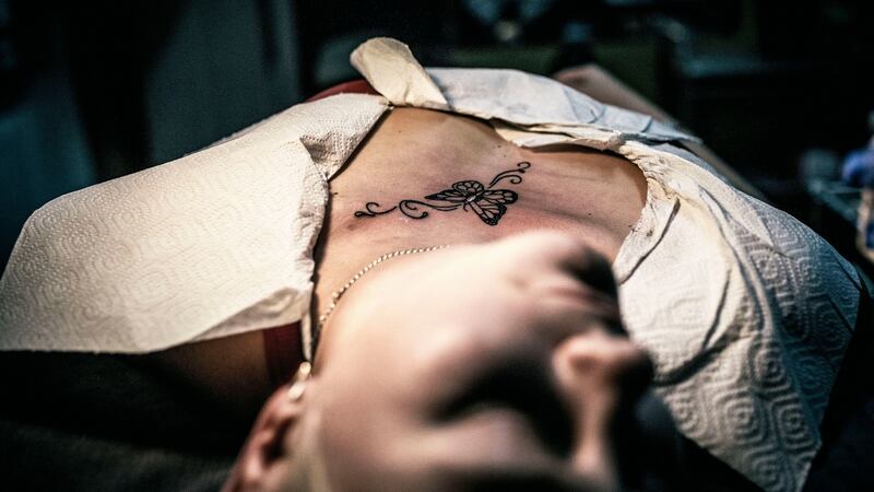 In this photo Viktoria lies on a  bed  to get a tattoo done to conceal a scar from a domestic violence attack. Photograph: Vadim Braydov/AP