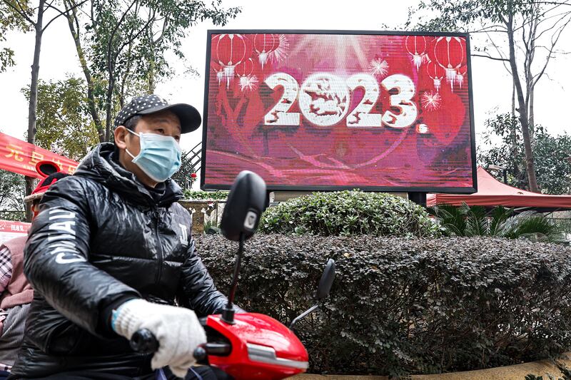 A man rides past a screen displaying the year 2023 on December 31st in Wuhan. Photograph: Getty Images