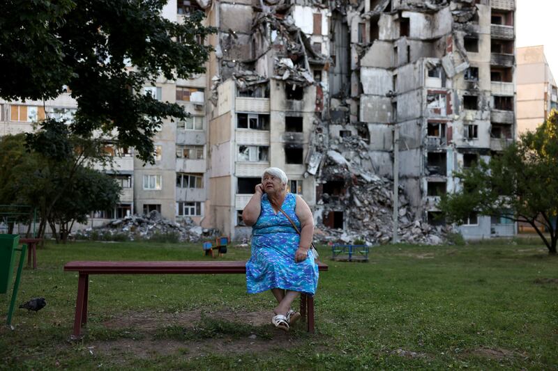A woman sits on a bench in front of a damaged apartment block, previously hit by a Russian missile strike, in Kharkiv, in August 2023. Photgraph: Cathal Mcnaughton/EPA-EFE