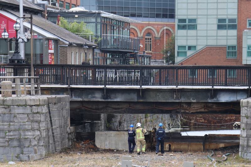 Gardaí and Dublin Fire Brigade personnel inspect the damaged George's Dock Bridge after a fire overnight. Photograph: Ronan McGreevy