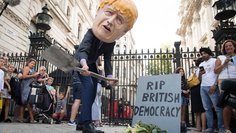 A person wearing a Boris Johnson ‘head’ digs a grave at the foot of a tombstone during a protest  outside Downing Street in London on Wednesday. Photograph: Stefan Rousseau/PA Wire