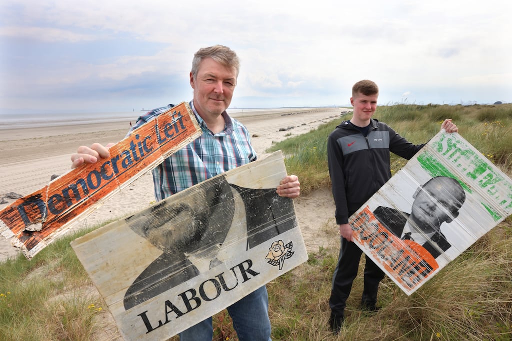 Brian Bolger from Kilbarrack, Dublin, and his son Colm with some old election posters found buried in the sand on Bull Island, Dollymount Strand, Dublin. Photograph: Dara Mac Dónaill