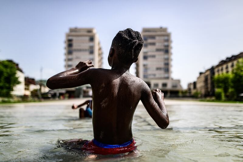 A child, seen from behind, sits in a shallow reflecting pool in Place Clemenceau in downtown Pau, Nouvelle-Aquitaine, France. Photograph: Quentin Top / Hans Lucas / AFP via Getty Images