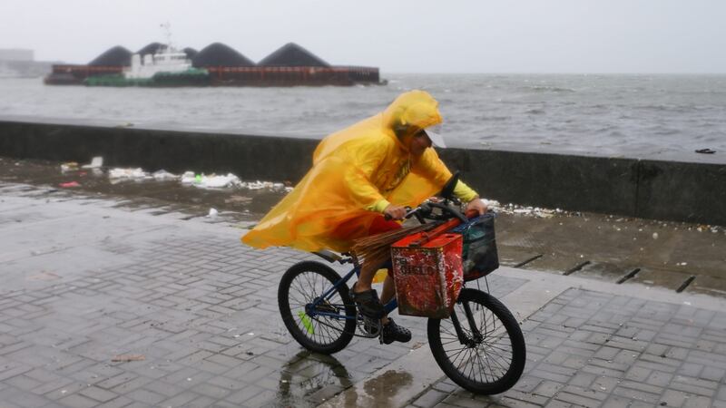 A man rides his bicycle as a shipping barge floats nearby at Manila Bay, in the Philippines on Sunday. Typhoon Koppu slammed into the northern Philippines forcing thousands of people to flee their homes amid heavy rains and strong winds that could last up to three days, the disaster relief agency said. Photograph: Mark R Cristino/EPA