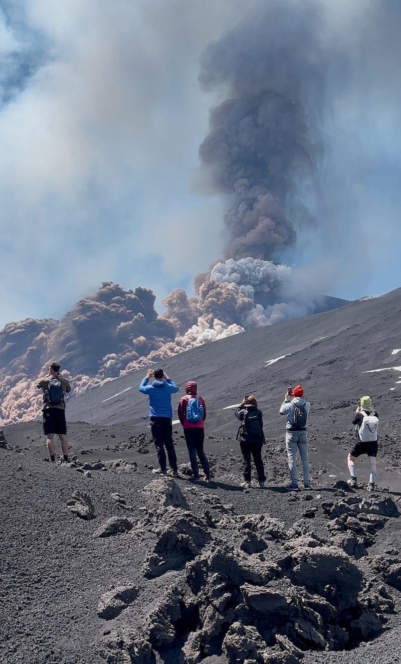 Sightseers watch as Mount Etna spews out clouds and debris. Photograph: Alex Stoian