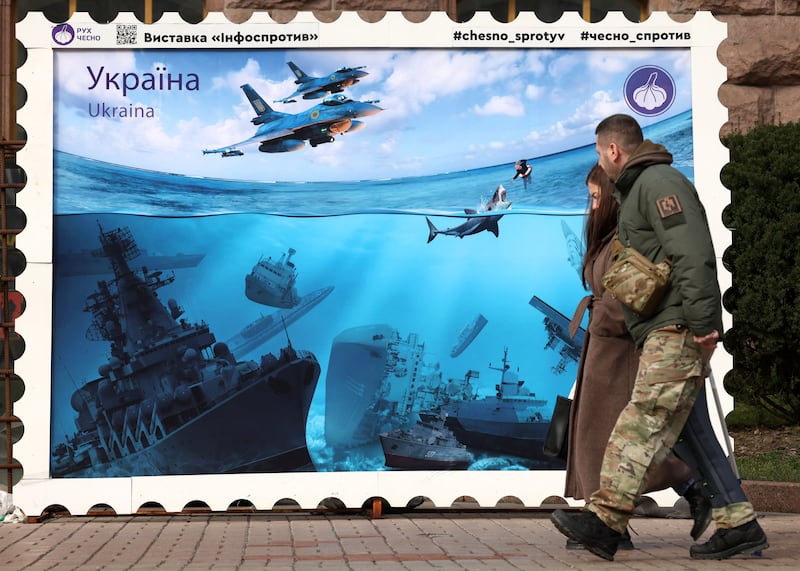 Pedestrians walk past artwork in Kyiv last year by the Chesno movement designed as a stamp depicting Russian warships sunk in the Black Sea after Ukrainian attacks. Photograph: Anatolii Stepanov/AF via Getty Images