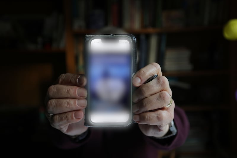 The Irish professor who lost more than €1 million to investment scammers holds up a phone showing a website used as part of the scam operation supposedly based in Switzerland. Photograph: Alan Betson