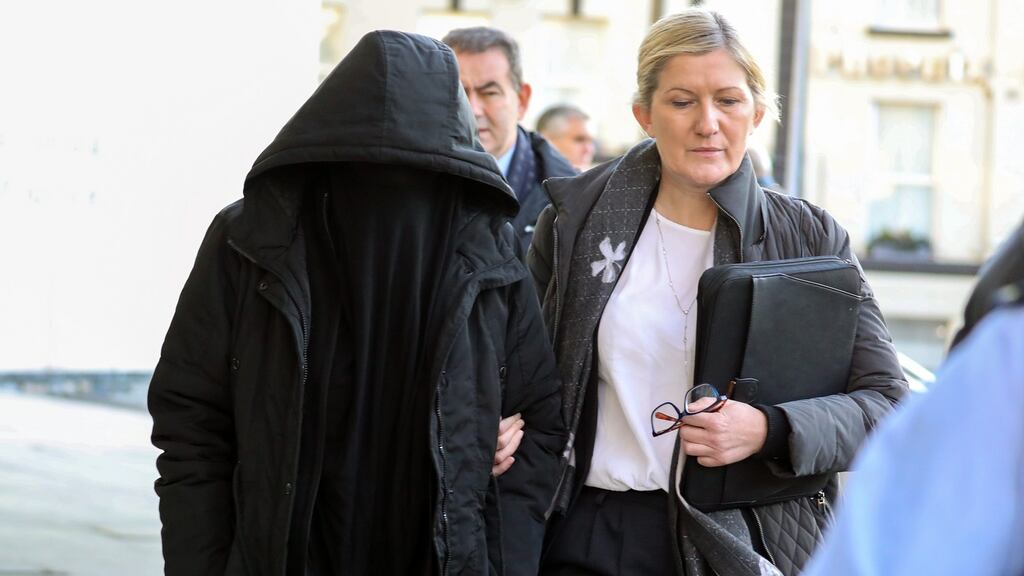 Lisa Smith (38) (left, covered) is escorted by a Garda member leaving the Criminal Courts of Justice, Dublin on Tuesday morning. Photograph: Collins Courts
