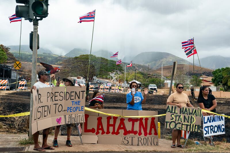 Residents of Lahaina hold signs as President Joe Biden's motorcade passes through during his visit. Photograph: Haiyun Jiang/The New York Times
                     