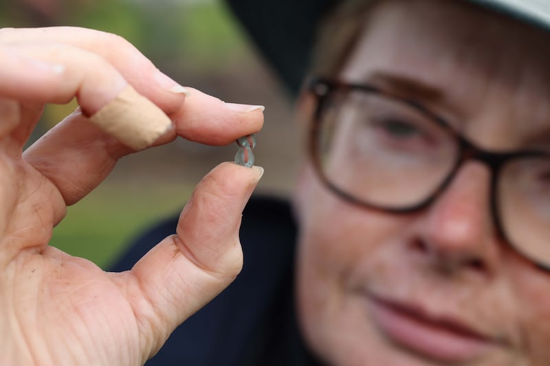 Dr Michelle Comber holding a turquoise and red glass bead found at the Rathgurreen Ringfort and believed to date from early medieval Ireland. Credit: Aengus McMahon
