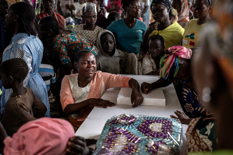 Mourners gather around the coffins of three people who died within 24 hours of each other at Kigonze camp in Bunia, Ituri province. Photograph: Finbarr O'Reilly/The New York Times
                      