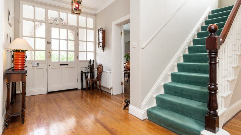 The bright square hall is floored in narrow oak planks.