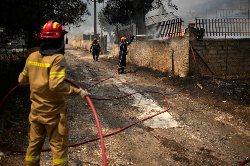 Firefighters tackle flames at a house in Acharnes, north of Athens. Photograph: Thanassis Stavrakis/AP