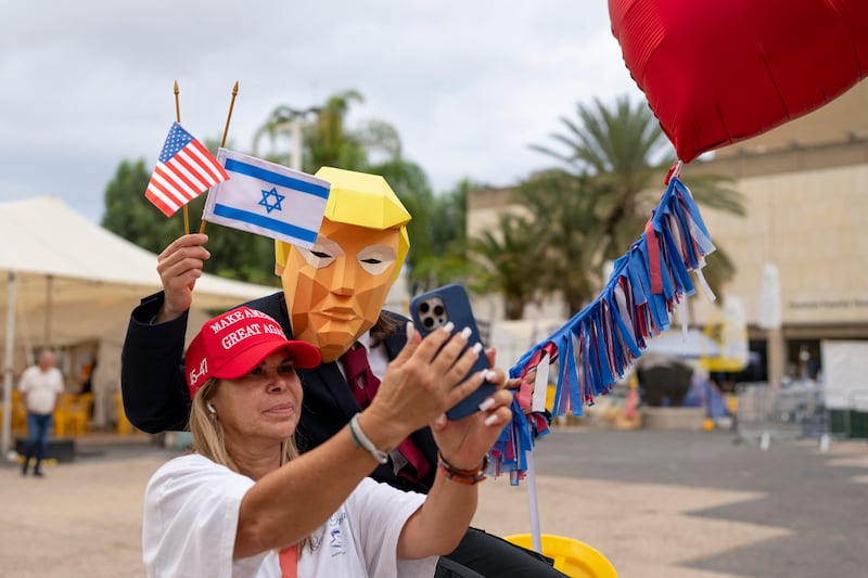 A person wearing a mask depicting US president Donald Trump holds US and Israeli flags after the hostage deal declared by Trump, at Hostage Square in Tel Aviv. Photograph: Maya Levin/AFP via Getty Images         