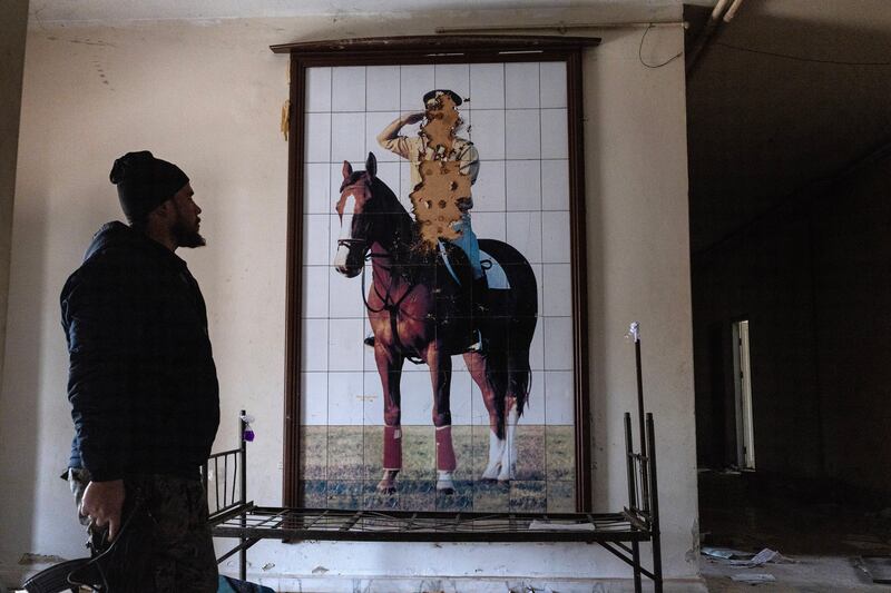 A rebel fighter stands in front of a defaced mural of Bashar Assad inside a captured police station in Homs, Syria in 2024. Photograph: David Guttenfelder/New York Times