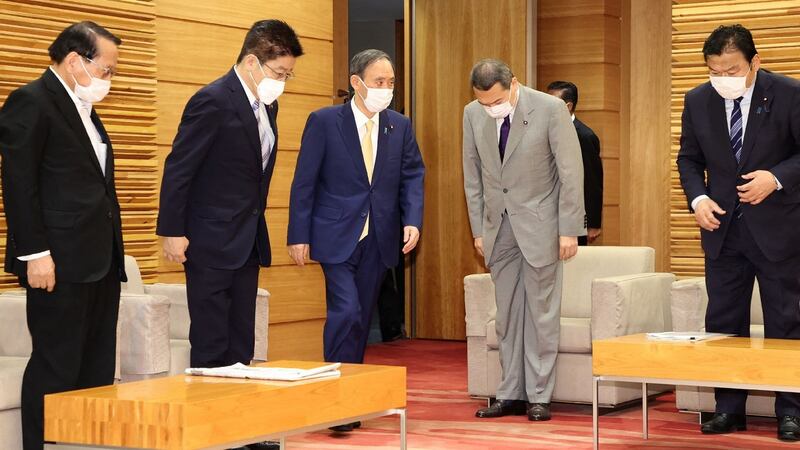 Japan’s prime minister Yoshihide Suga (centre, blue suit) arrives to attend a cabinet meeting at the prime minister’s office in Tokyo on Tuesday. Photograph:  STR/Jiji Press/AFP via Getty Images