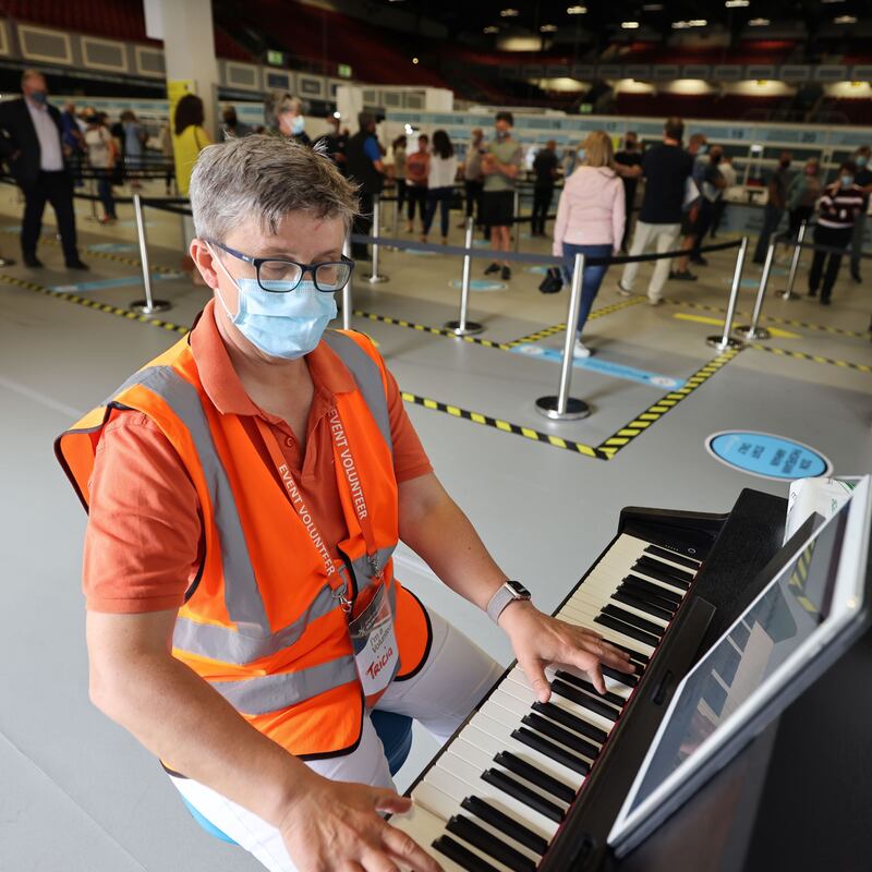 Tricia Nolan, manager of the South Dublin County Volunteer Centre, playing the piano as people queue at the Citywest vaccination centre. Photograph: Alan Betson